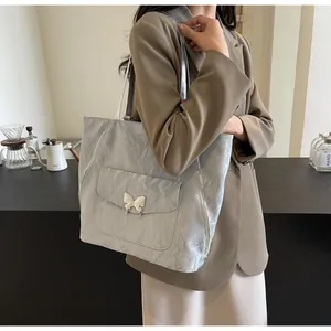 Close-up of silver tote bag showing crinkled texture and metallic butterfly buckle detail