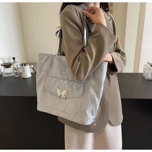 Detail of silver tote bag with crinkled texture, butterfly buckle and decorative zippers