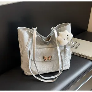 Detailed shot of silver tote bag with metallic butterfly buckle and fuzzy cloud charm