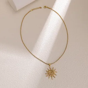 Dettaglio della collana dorata con pendente a sole a spirale e catena a serpente