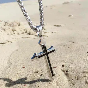 Pendentif croix gothique en acier inoxydable argenté sur fond de plage de sable fin