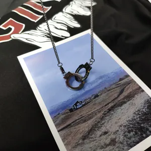 Détail du collier menottes en acier titane avec gravure UNLOCK sur fond urbain chic