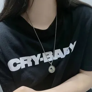 Detailed view of silver astronaut necklace on black t-shirt for modern hip-hop styling