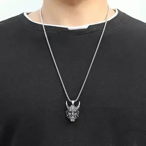 Close-up of vintage silver Hannya mask pendant on a metal chain worn on black clothing
