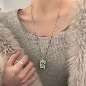 Detail view of a hip hop mahjong pendant with green crystals on a silver beaded chain
