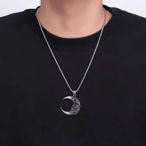 Detail of vintage silver moon pendant with embossed rose worn on black shirt