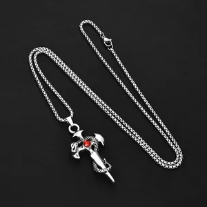 Detail of silver gothic cross pendant with red gemstone and coiled dragon on black background