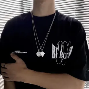 Detail von silbernen Puzzle-Halsketten für Paare an einem Street-Fashion-Model im Licht