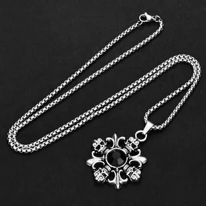 Detailed shot of gothic silver skull pendant with black gemstone and fleur-de-lis engraving