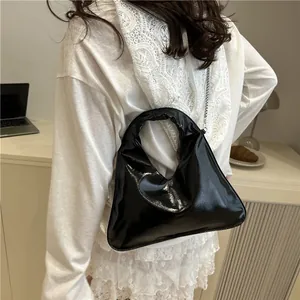 Sleek black glossy crossbody bag with silver chain and modern cutout handle design