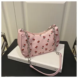 Detail of pink shoulder bag featuring red cherry prints and silver chain strap
