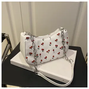 Close-up of white shoulder bag with cherry pattern, silver chain, and textured PU leather