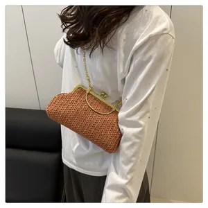Vue détaillée de la pochette en paille marron avec cadre doré et bandoulière