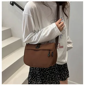Detail of the brown waterproof crossbody bag with wide strap and zip pockets