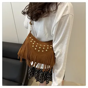 Détail d'un sac bandoulière vintage en daim caramel avec clous dorés et franges