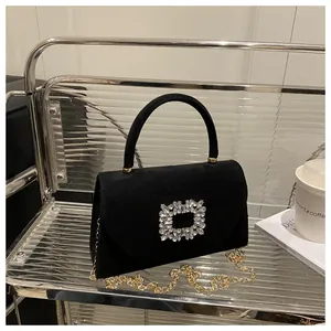 Dettaglio borsa in camoscio nero con fibbia di strass e tracolla a catena dorata