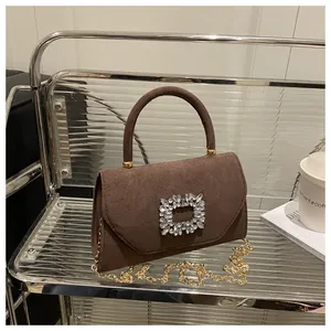 Dettaglio borsa in camoscio marrone con lussuosa fibbia quadrata oversize in cristallo