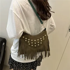 Sac hobo rétro en daim marron avec rivets dorés et franges porté à l'épaule