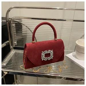 Dettaglio della borsa in pelle scamosciata bordeaux con fibbia di strass e catena d'oro