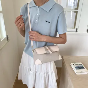 Sac baguette beige en texture tressée avec bordure en cuir et boucle dorée sur modèle