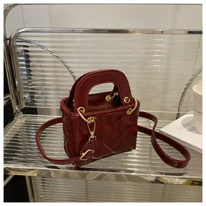 Detailed shot of burgundy quilted leather mini bag with gold hardware on a glass shelf