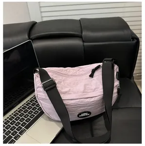 Dettaglio borsa a mezzaluna in nylon lilla con patch Lucky Fashion su sfondo in pelle nera