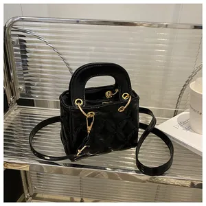 Detail of black patent leather crossbody bag with classic diamond quilting and gold hardware