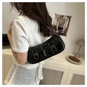 Détail d'un sac sous les aisselles rétro noir en cuir brillant avec boucles métalliques