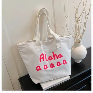 Détail du sac cabas en toile blanche avec imprimé lettres roses sur un support