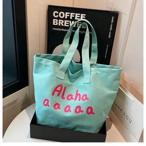 Gros plan du sac cabas en toile vert menthe avec imprimé artistique rose et anses solides