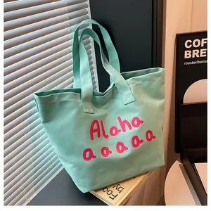 Détail d'un cabas en toile vert menthe avec lettrage Aloha rose dans un décor intérieur