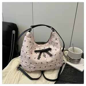 Dettaglio della borsa a secchiello rosa con fiocco, nastro nero e ciondolo a cuore
