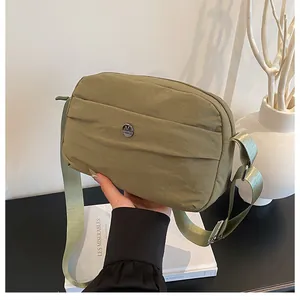 Macro detail of olive green nylon crossbody bag with metallic logo and pleated design