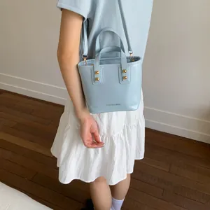Light blue faux leather bucket bag with gold rivets and detachable crossbody strap