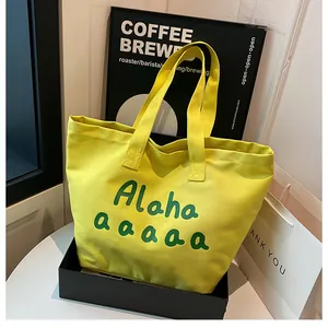 Gros plan d'un cabas en toile jaune avec imprimé artistique dans une boîte cadeau noire