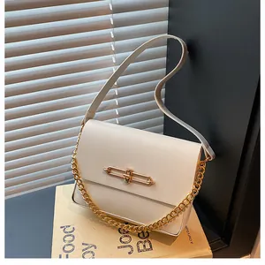 Detail of cream white leather bag showing the golden metal bar clasp and shadow lighting