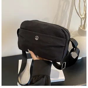Detail of black nylon shoulder bag featuring silver M logo and wide adjustable strap