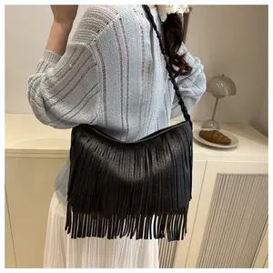 Détail d'un sac à bandoulière noir à franges bohème avec bandoulière tressée porté