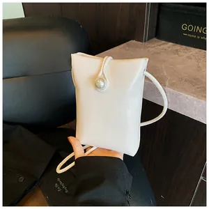 Detail of white mini crossbody bag with glossy finish and elegant pearl clasp decoration