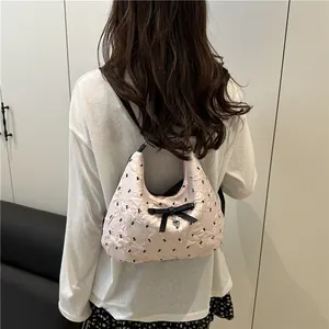 Borsa a secchiello trapuntata rosa con fiocco nero e ciondolo a cuore sulla spalla