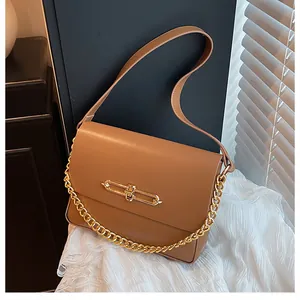 Detailed view of khaki brown leather crossbody bag with elegant gold metal lock and chain