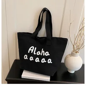 Détail d'un grand sac fourre-tout en toile noire avec lettrage blanc et style épuré
