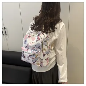 Close-up of stylish white backpack with colorful butterfly print and golden metal zippers