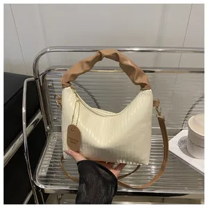 Detail of cream pleated handbag with brown handles and fashion tag in lifestyle setting