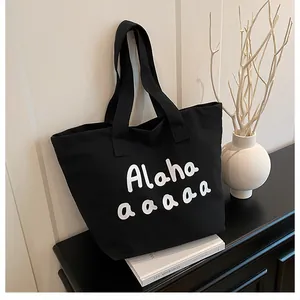 Vue détaillée d'un sac fourre-tout noir en toile avec lettrage blanc et style épuré