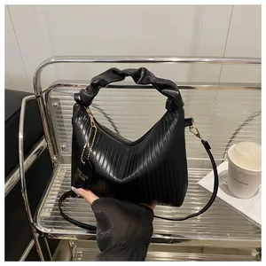 Macro detail of the vertical pleated texture and cloud-style handle on this black PU handbag