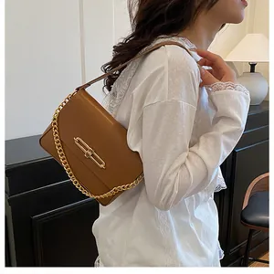 Side view of caramel crossbody bag with gold chain strap and metal lock detail on model