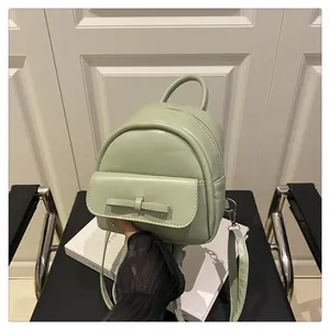 Detailed view of light green mini backpack with bow decoration and smooth PU leather texture