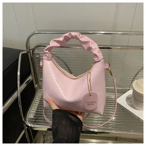 Detail of pink pleated handbag showing unique cloud handle and fashion leather tag