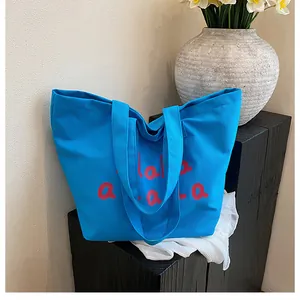 Gros plan du sac cabas en toile bleue avec imprimé rouge et grand espace de rangement